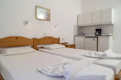 two beds in a room with a kitchen at Hotel Mimoza in Agia Marina Nea Kydonias