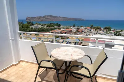 a balcony with a table and chairs and the ocean at Hotel Mimoza in Agia Marina Nea Kydonias