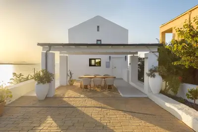 a white building with a table and chairs on a patio at Villa Anton by Cura Villas Collection in Kalathas