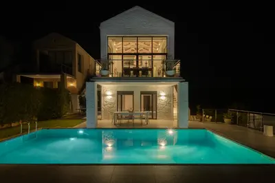 a house with a swimming pool at night at Villa Anton by Cura Villas Collection in Kalathas