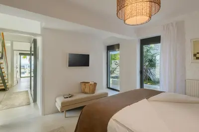 a bedroom with a bed and a television and a couch at Villa Anton by Cura Villas Collection in Kalathas