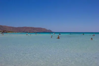 a group of people in the water at the beach at Esthisis Suites Chania in Plataniás