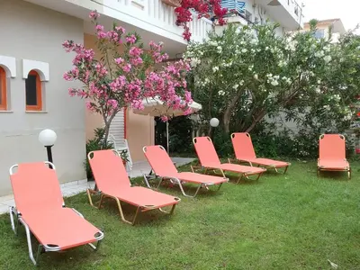 a group of red chairs sitting in the grass at Ilona Apartments Chania in Kato Daratso