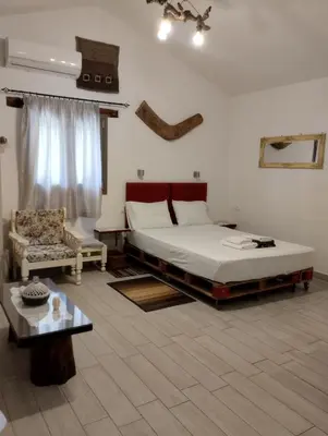 a bedroom with a large bed and a chair at Olea Cottage in Galatás