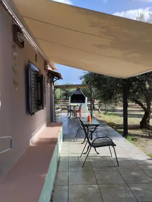 a patio with tables and chairs and a grill at Olea Cottage in Galatás