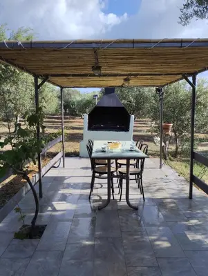 a patio with a table and chairs and a grill at Olea Cottage in Galatás