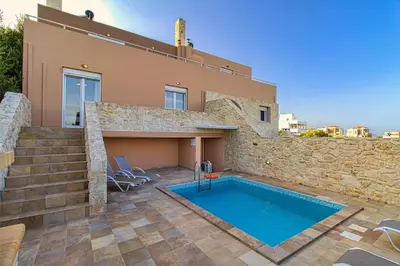 a villa with a swimming pool in front of a house at Theo Villas With Sea View in Marathokefála