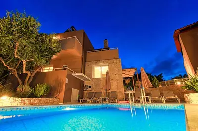 a villa with a swimming pool at night at Theo Villas With Sea View in Marathokefála