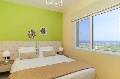 a bedroom with a large bed with a large window at Theo Villas With Sea View in Marathokefála