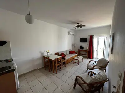 a living room with a couch and a table and chairs at Michael Apartments in Agia Marina Nea Kydonias