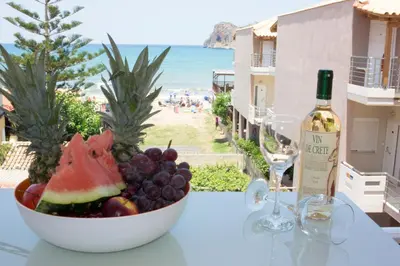 a bowl of fruit on a table with a bottle of wine at Michael Apartments in Agia Marina Nea Kydonias