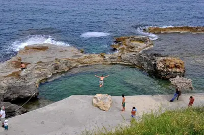 a man jumping into the water in a rock pool at Amazing Sea View Apartment in Chania Town
