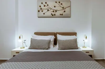 a bedroom with a bed with pillows and two lamps at Deluxe Hotel in Chania Town