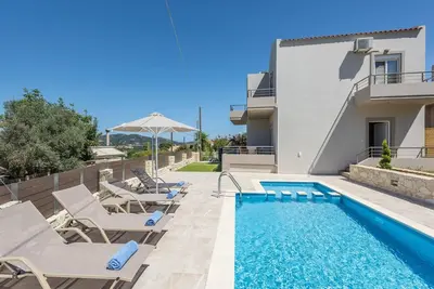 a villa with a swimming pool and patio furniture at Villa Neaira in Vatólakkos