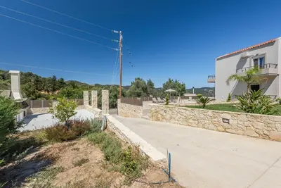 a building with a stone wall next to a sidewalk at Villa Neaira in Vatólakkos