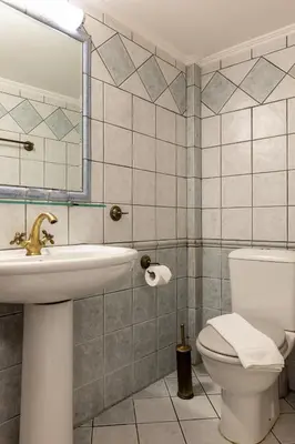 a bathroom with a sink and a toilet and a mirror at Vilelmine in Chania Town
