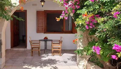 a patio with a table and chairs and flowers at Doma Apartments in Falasarna