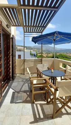 a patio with a table and chairs and an umbrella at Doma Apartments in Falasarna
