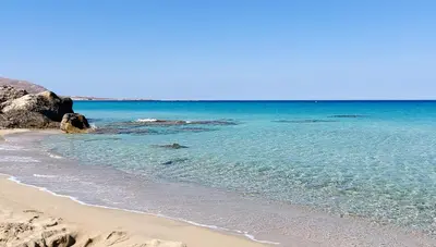 a beach with the blue water and rocks at Doma Apartments in Falasarna