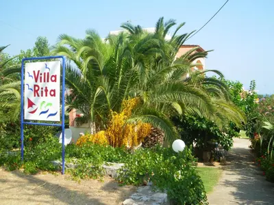 a sign in front of a palm tree at Villa Rita Apartments A in Tavronitis