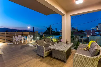 a patio with chairs and a table on a deck at night at SUPERIOR VILLA MARINA MARE Sauna - Hammam - Pool - 250m from Beach in Agia Marina Nea Kydonias