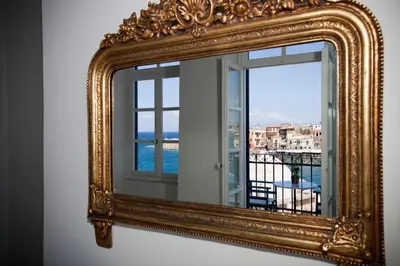 an ornate gold mirror on a wall with a window at Suites Pandora in Chania Town