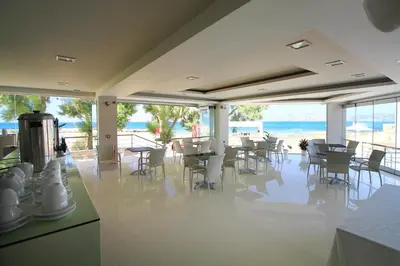 a dining room with tables and chairs and the ocean at Nautilus Bay Hotel in Kissamos