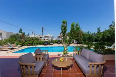 a patio with chairs and a table next to a pool at Villa Armonia Chania in Kato Galatas