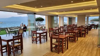 a restaurant with tables and chairs and the ocean at Sunny Bay Hotel in Kissamos