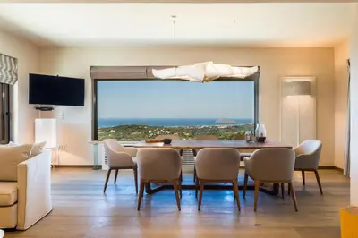 a dining room with a table and chairs and a large window at Angel Hill Villa in Xirokámbion