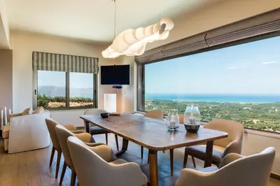 a dining room with a table and chairs and a large window at Angel Hill Villa in Xirokámbion