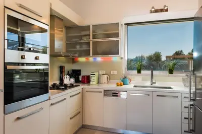 a kitchen with white cabinets and a large window at Angel Hill Villa in Xirokámbion