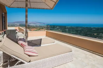 a balcony with a couch and an umbrella at Angel Hill Villa in Xirokámbion