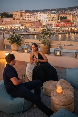 two men sitting on the roof of a building with drinks at Casa Delfino Hotel & Spa in Chania Town
