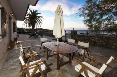a patio with a table and chairs and an umbrella at Pericles Beach Villa in Kissamos