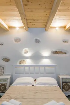 a bedroom with a bed with white walls and wooden ceilings at Minos Villa in Arménoi