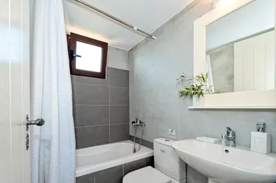 a bathroom with a sink and a toilet and a tub at Minos Villa in Arménoi