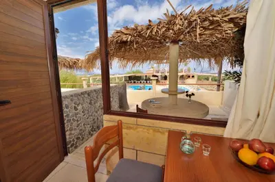 a dining room with a table and a view of a pool at Anemomili Village in Kissamos