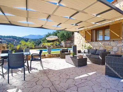 a patio with a table and chairs and an umbrella at Villa Vangelis Stylos Crete in Khiliomoudhoú