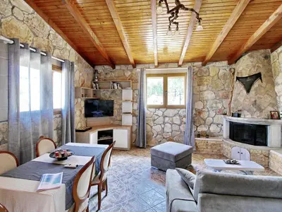a living room with a table and a stone wall at Villa Vangelis Stylos Crete in Khiliomoudhoú