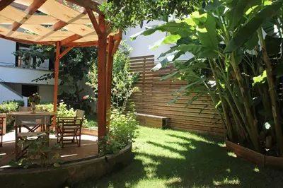 a garden with a table and chairs under a wooden pergola at Gardens Downtown center Chania Elpida Villa in Chania Town
