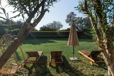 a patio with two chairs and an umbrella and a lawn at Wooden Beach House in Gerani Chanion
