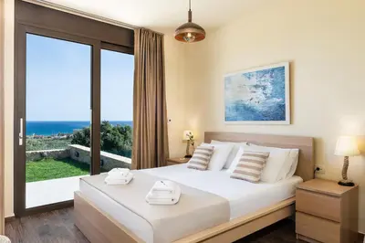 a bedroom with a large bed with a large window at Villa Kudos in Maleme