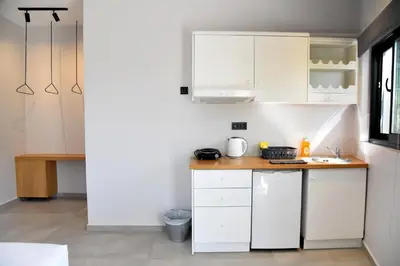 a small kitchen with white cabinets and a sink at Galini Studios & Apartments-Adults only in Sougia