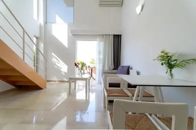 a white living room with a table and chairs at Lotus Hotel Apartments in Kato Daratso