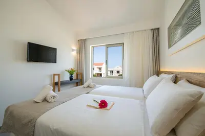 a bedroom with a large white bed with flowers on it at Lotus Hotel Apartments in Kato Daratso