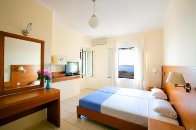 a bedroom with a bed and a mirror and a sink at Giorgi's Blue Apartments in Kalathas