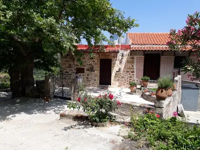 a brick house with a tree and some flowers at Traditional House Koukounara in Kissamos