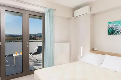 a bedroom with a bed and a balcony at Jasmine in Maleme