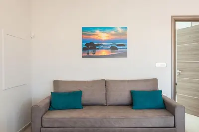 a couch in a living room with a painting on the wall at Mimosa in Maleme